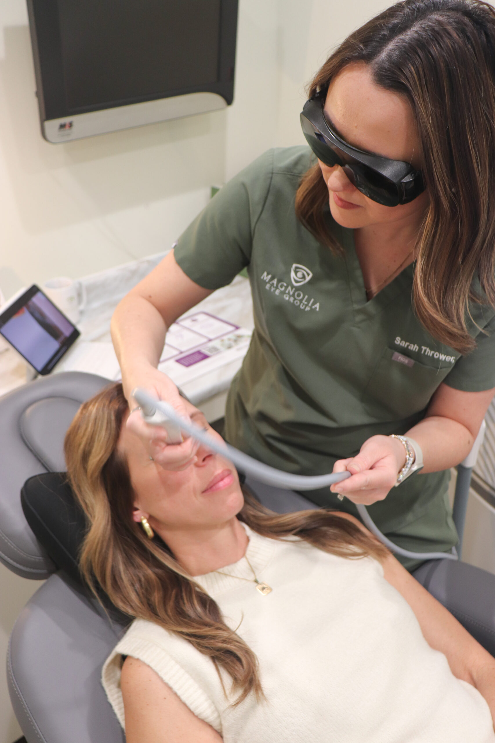 Dr. Taylor Edwards at Work – Magnolia Eye Group Dr. wearing green scrubs, focuses on a client while working at Magnolia Eye Group. – Magnolia Eye Group