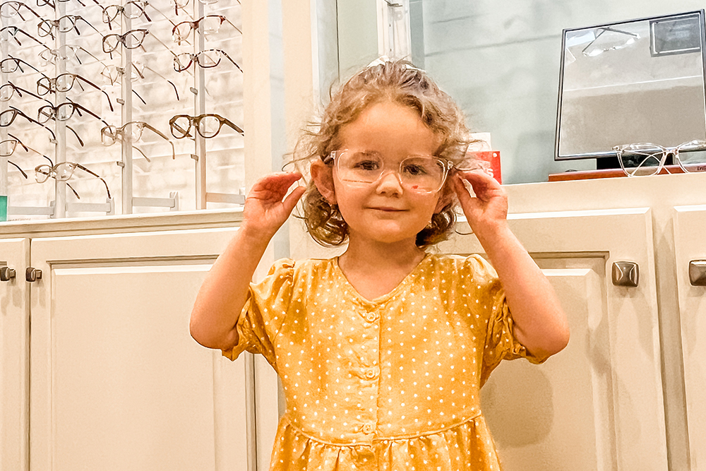 little girl in yellow wearing eye glasses